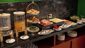 A buffet with various food items, including pastries, fruits, and salads, arranged on a marble countertop. - NiK Hotel Thi Sach (Ho Chi Minh City)