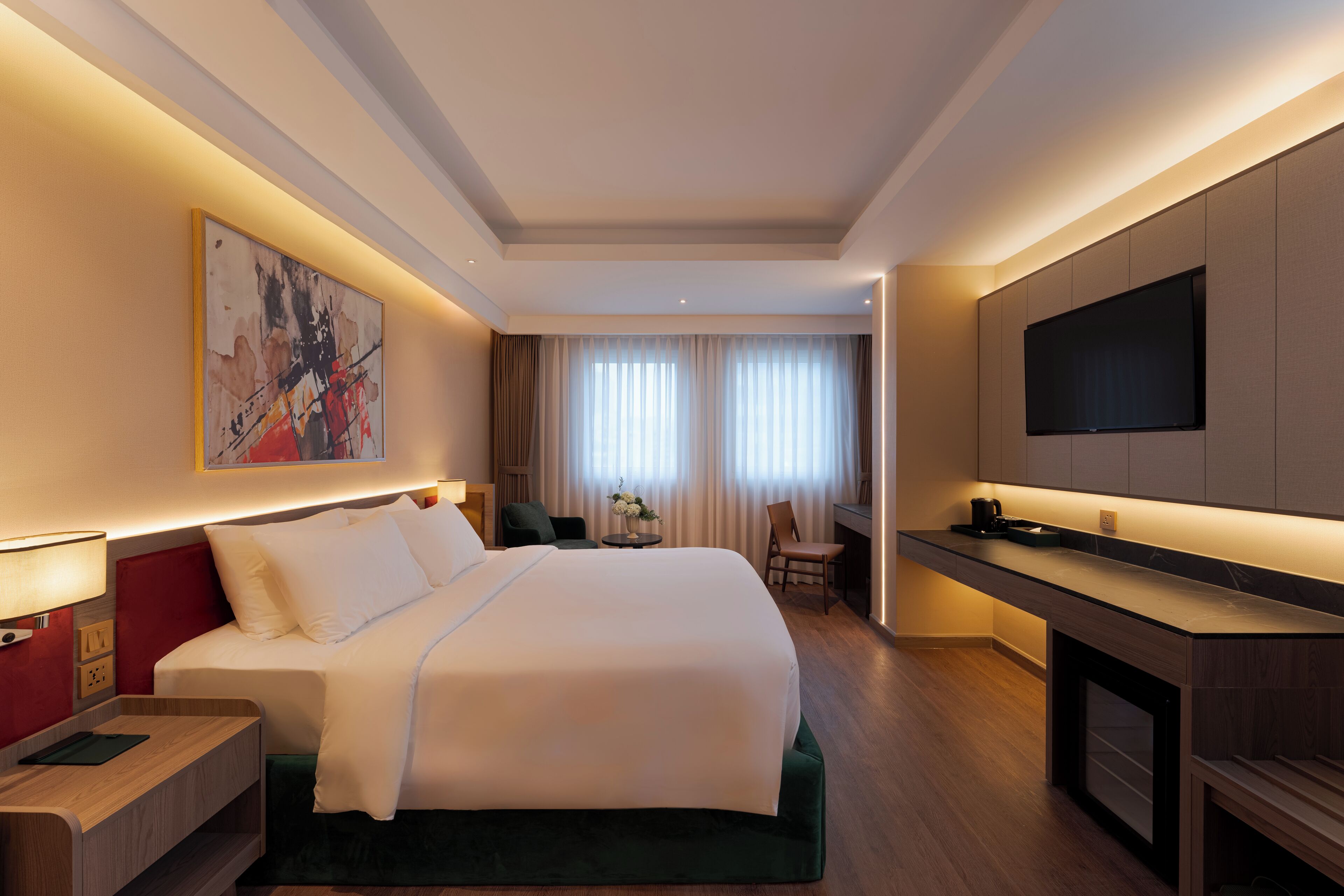 Une chambre d’hôtel avec un grand lit, un bureau, un téléviseur à écran plat et un tableau au mur.