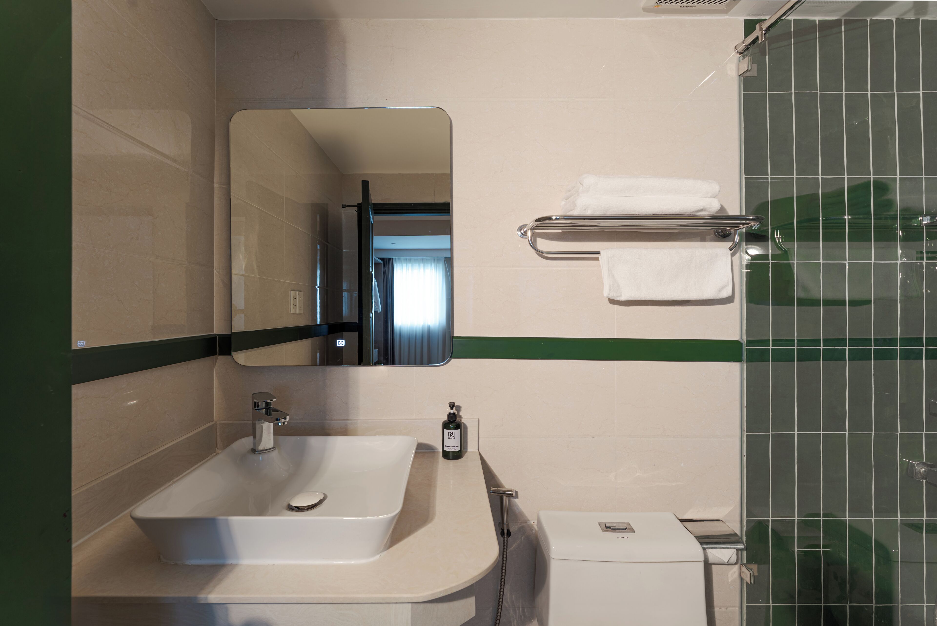 Un baño con lavamanos, espejo, toallero y ducha.