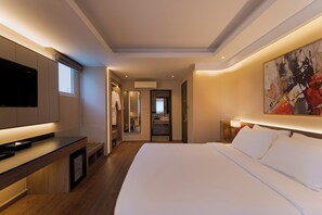 A modern hotel room with a large bed, a flat-screen TV, a desk, and a bathroom visible through an open door. - NiK Hotel Thi Sach (Ho Chi Minh City)