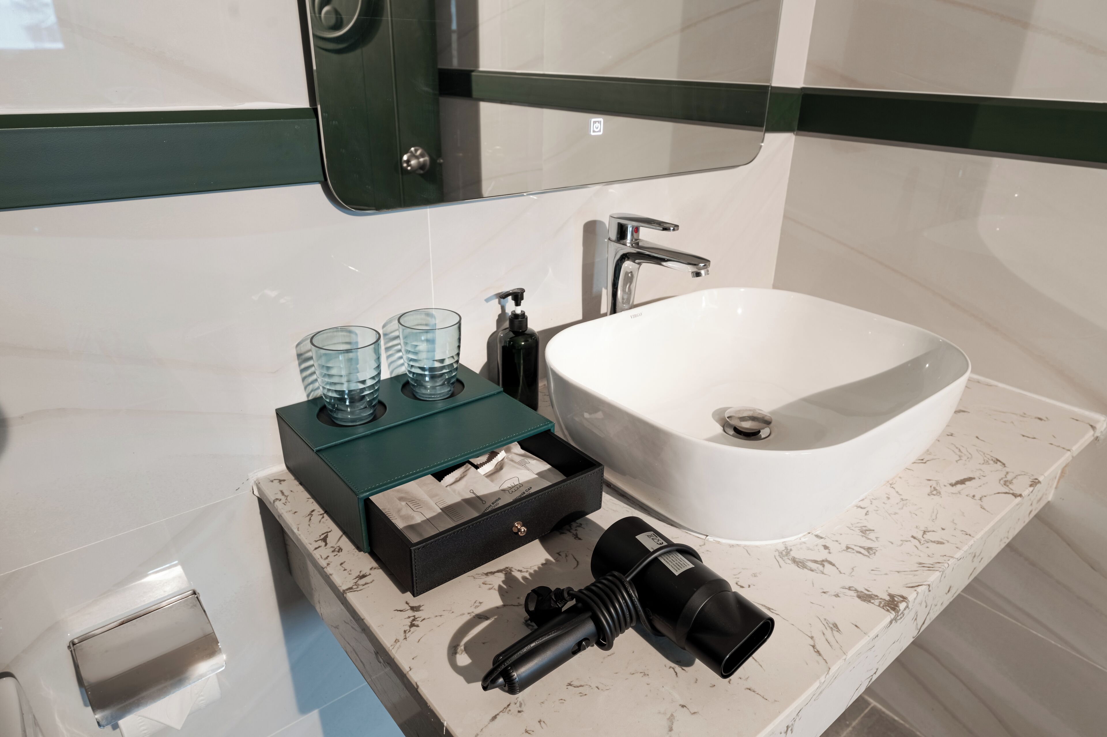 Casa de banho com lavatório branco, espelho e armário de vidro com produtos de higiene pessoal.