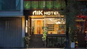 A hotel entrance with a modern facade, illuminated signage, and a staircase leading to the entrance. - NiK Hotel Thi Sach (Ho Chi Minh City)