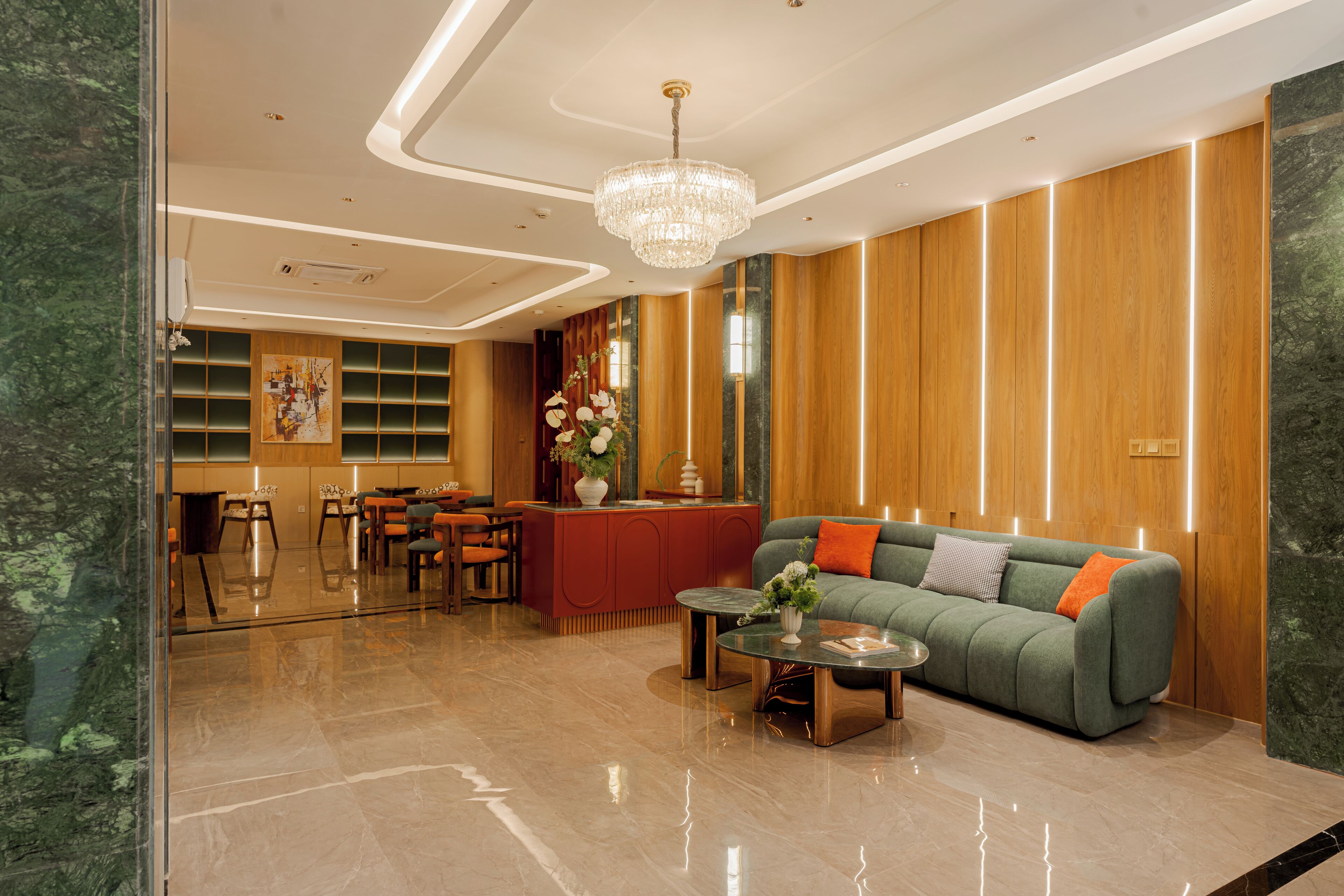 Een moderne lobby met een receptiebalie, een zithoek en een kroonluchter.