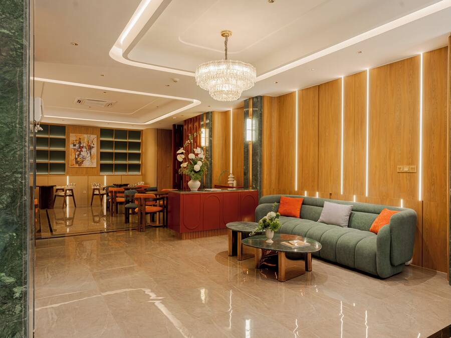 Een moderne lobby met een receptiebalie, een zithoek en een kroonluchter.