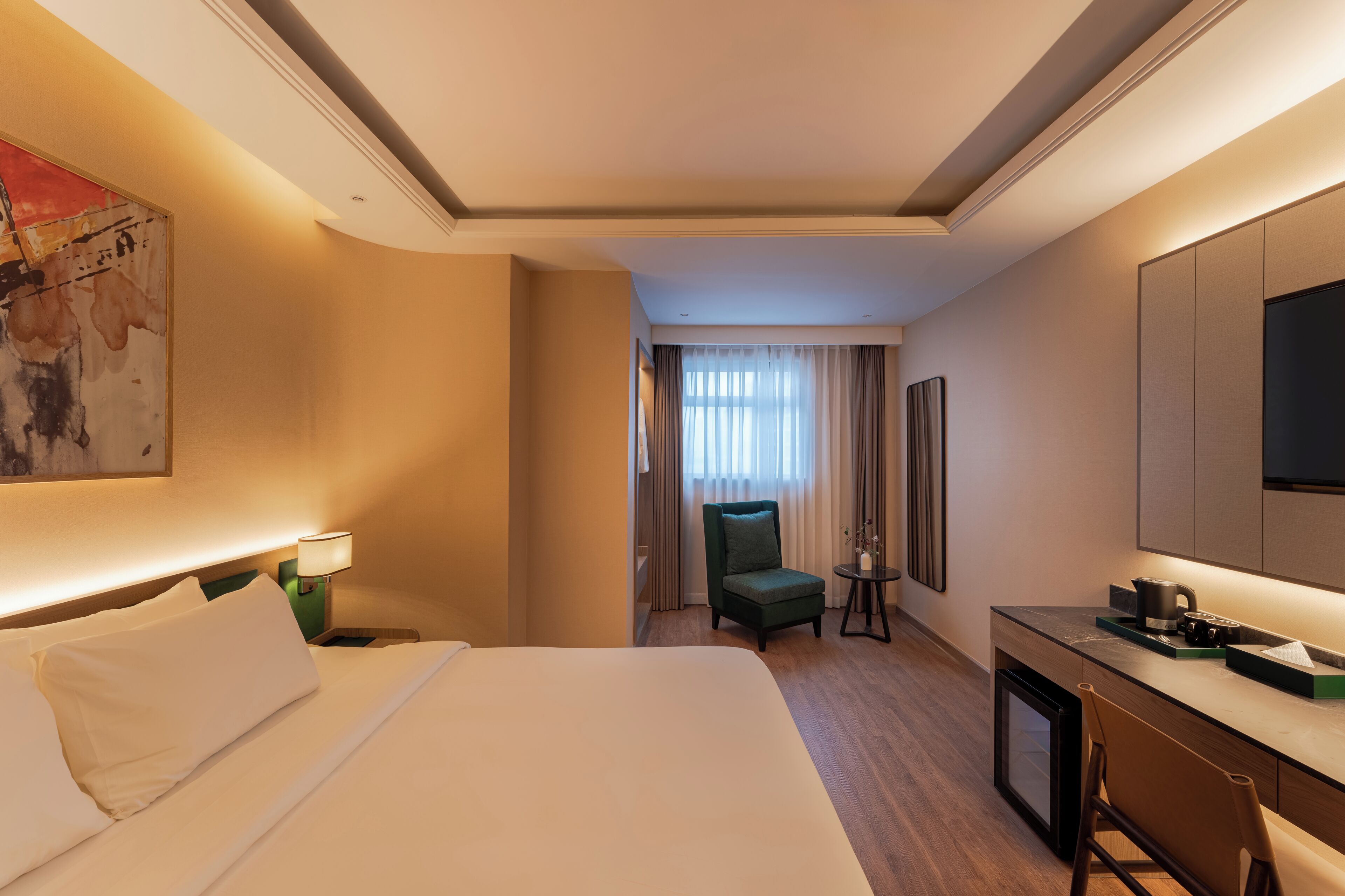 Hotellihuone, jossa on suuri sänky, työpöytä, kahvinkeitin, tuoli ja televisio.