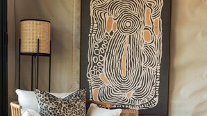 A cozy seating area with a sofa, a wooden side table, and a large abstract painting on the wall.