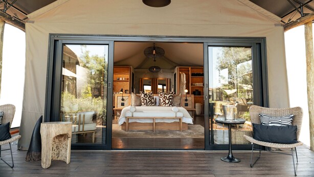 A spacious bedroom with a large bed, a sitting area with chairs, and a dining table.