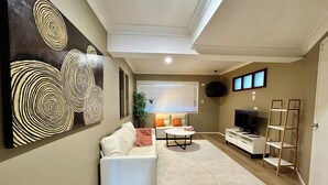 Een woonkamer met een bank, televisie en kunst aan de muur.