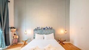 Een slaapkamer met een groot bed, twee nachtkastjes, een plant en een wandlamp.