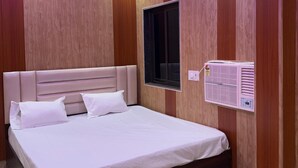 A bedroom with a bed, a ceiling fan, and a wall-mounted air conditioner. - Katyayani Palace (Faizabad)