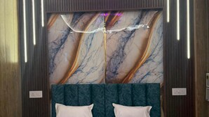 A modern bedroom with a large bed, a marble-patterned headboard, and vertical light fixtures. - Katyayani Palace (Faizabad)