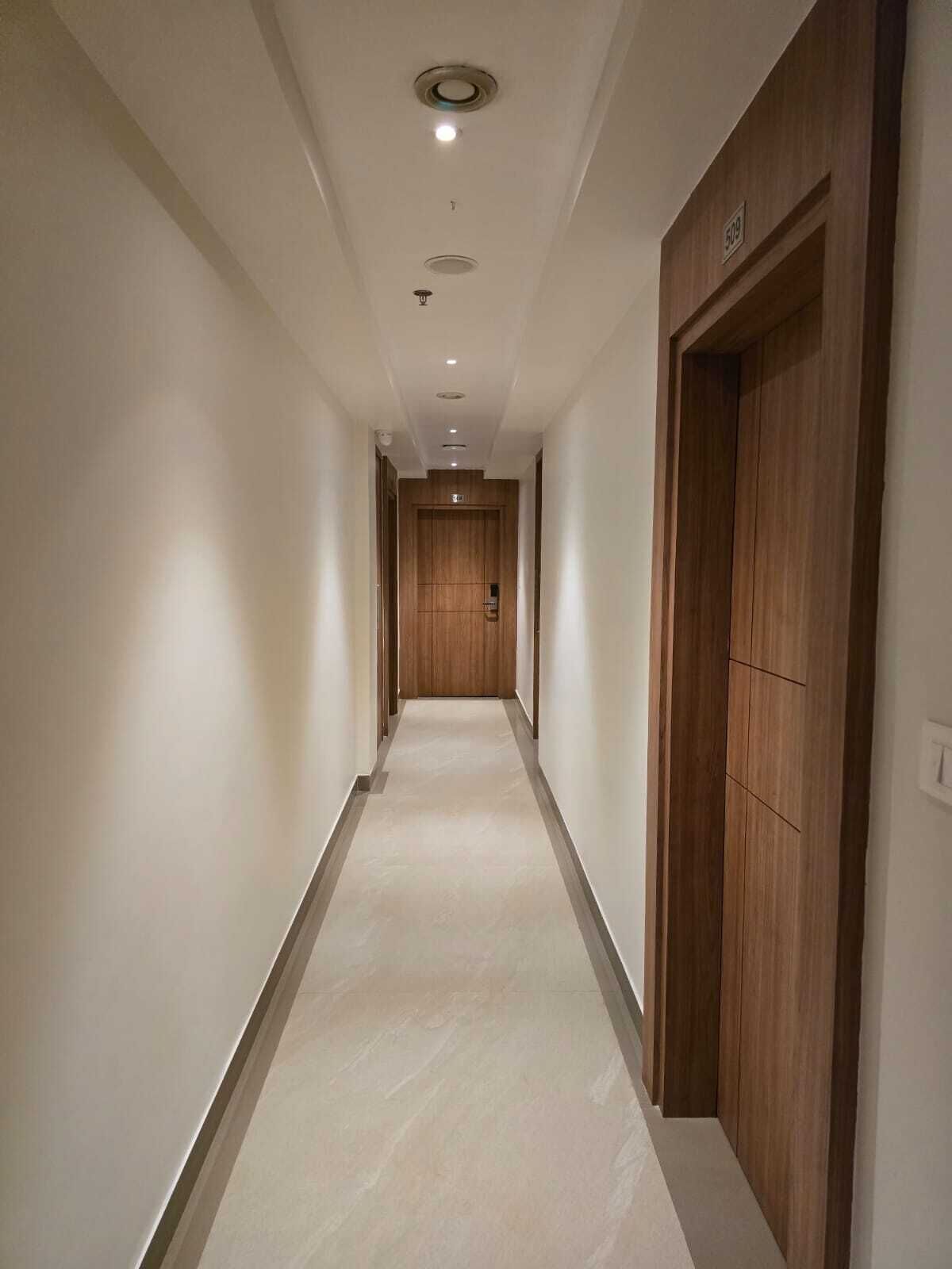 Ein Korridor mit einer Holztür am Ende, einer Deckenleuchte und einem an der Wand montierten Lichtschalter.