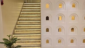 Eine Treppe mit beleuchteten Stufen, ein Blumentopf und eine Wand mit vielen kleinen Fenstern.