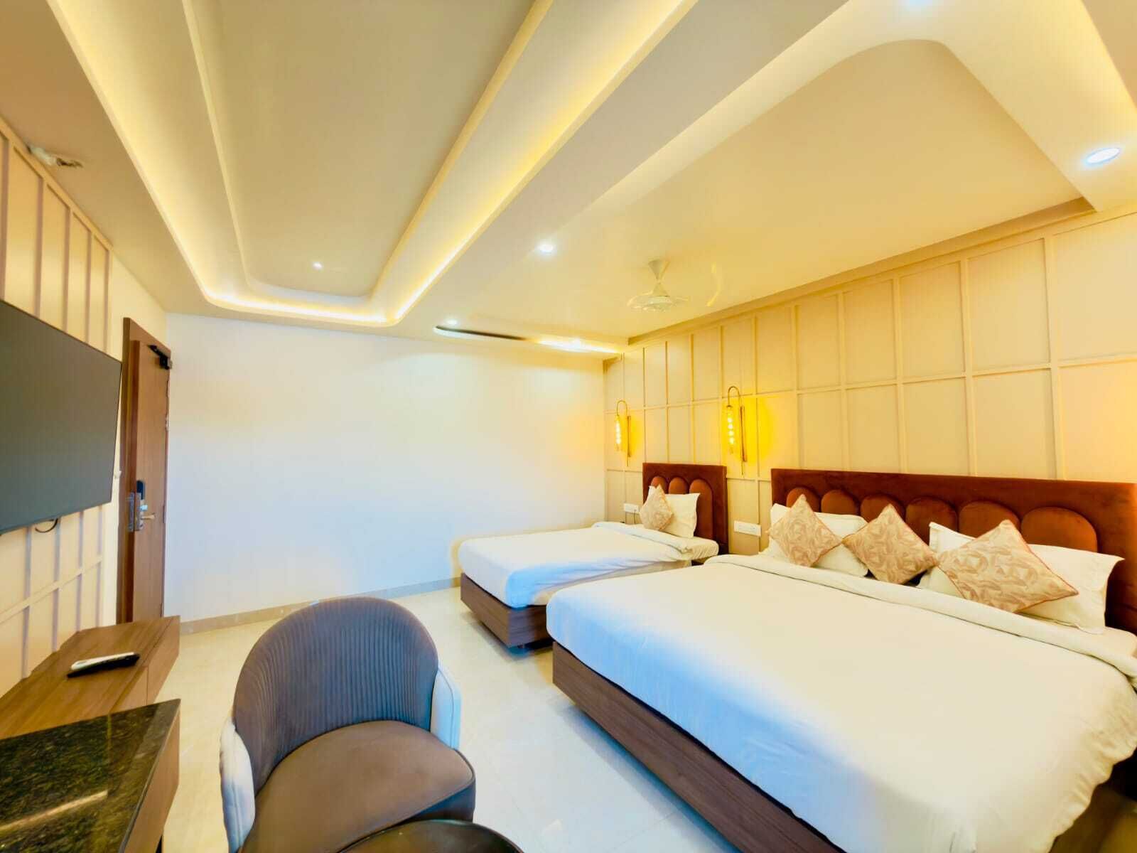 Habitació d'hotel amb dos llits, un escriptori, una cadira i una televisió.