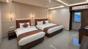 Ein Hotelzimmer mit zwei Betten, Wandleuchten, einem Deckenventilator und einem Fenster mit Jalousien.