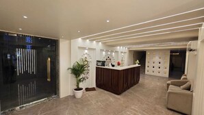 Eine moderne Hotelhalle mit einer Rezeption, einem Topf mit Pflanze, einer Couch und einer Wanddekoration.
