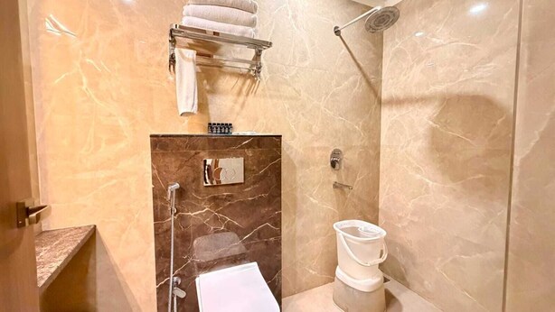A modern bathroom with a marble shower, a toilet, and a sink. - Hotel Sanidhyam bliss Varanasi (Varanasi)