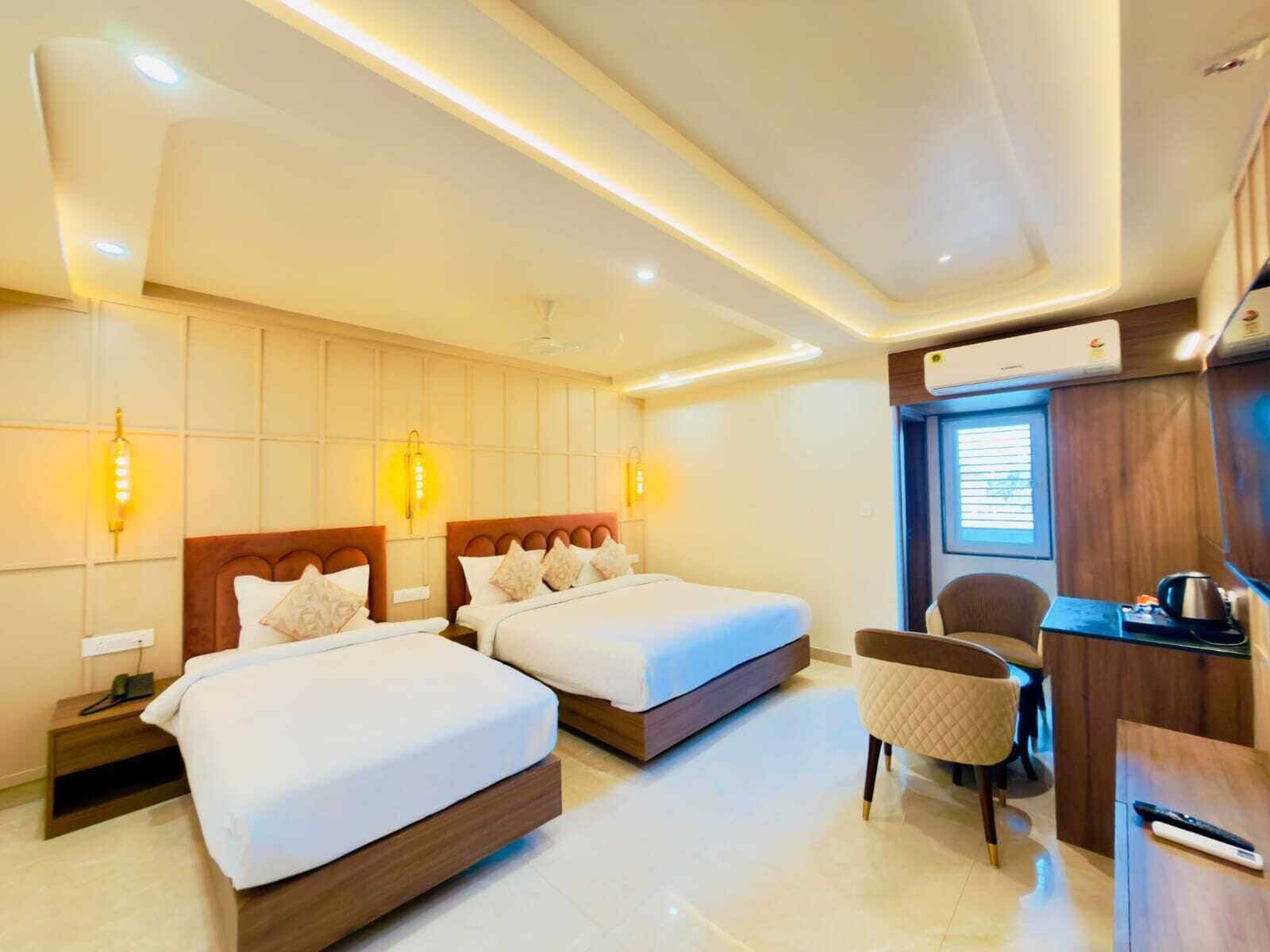 A hotel room with two beds, a desk, a chair, and an air conditioning unit.