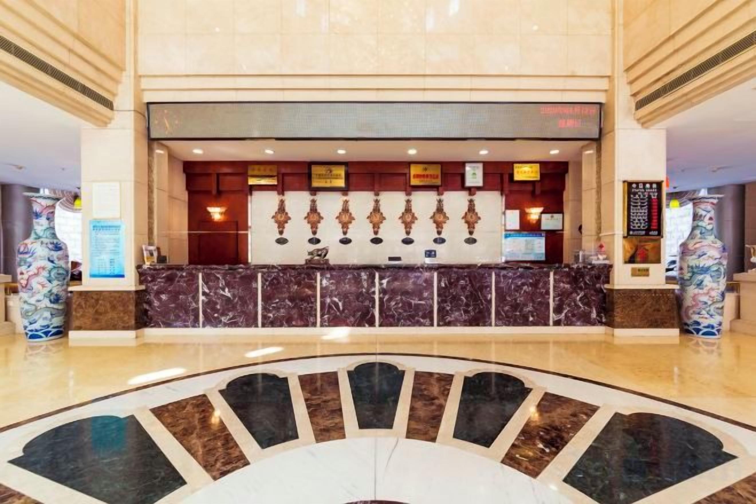 Zona de recepción de hotel con mostrador de mármol, un jarrón grande y diseño moderno.