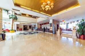 A spacious lobby with a central fountain, a palm tree, and a reception desk. - Cangzhou Yihe Hotel (Cangzhou)