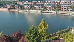 Zona residencial frente al río con modernos edificios de apartamentos, un río tranquilo y abundante vegetación.