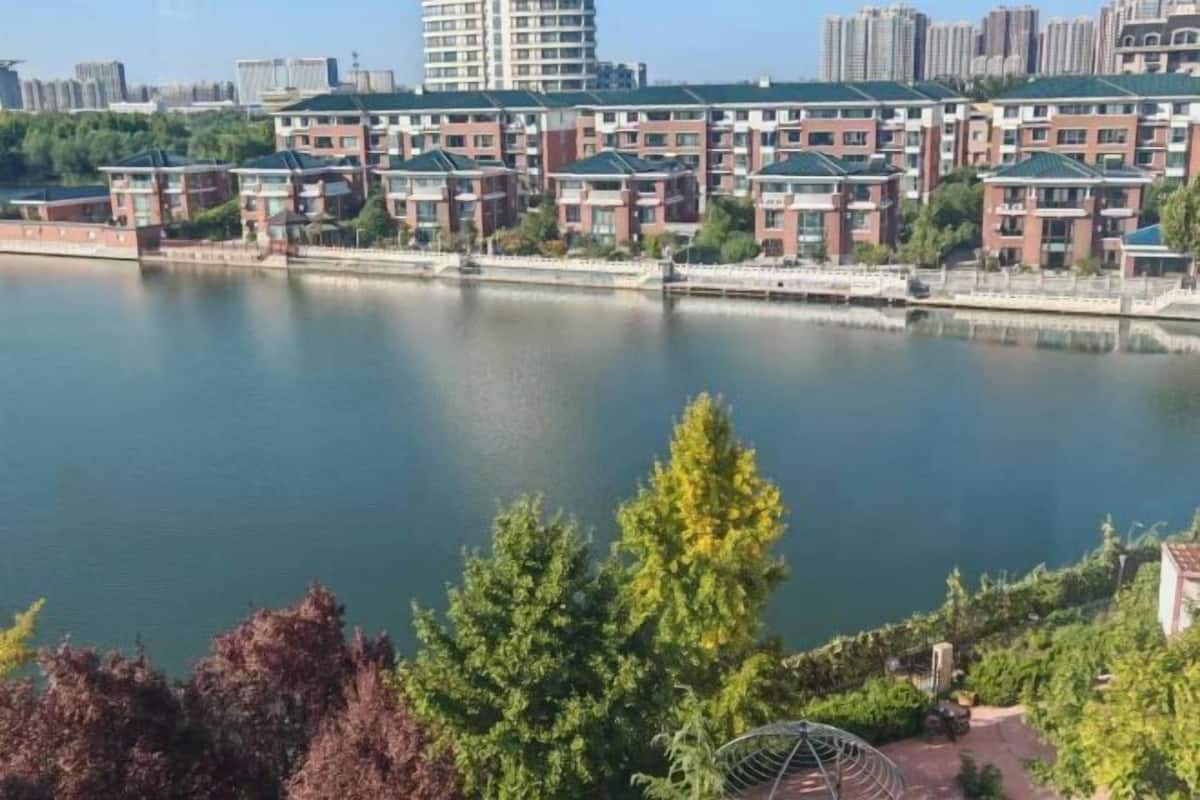 A waterfront residential area with modern apartment buildings, a calm river, and lush greenery.
