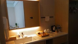 Un baño con un espejo grande, un lavabo y un perchero para toallas.