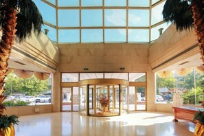 A lobby with a revolving door, large windows, and a palm tree. - Cangzhou Yihe Hotel (Cangzhou)