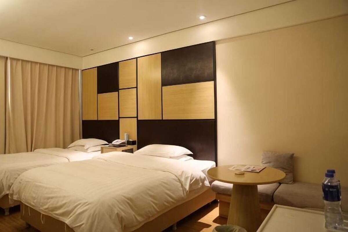 A hotel room with two beds, a round table, a chair, and a water bottle.