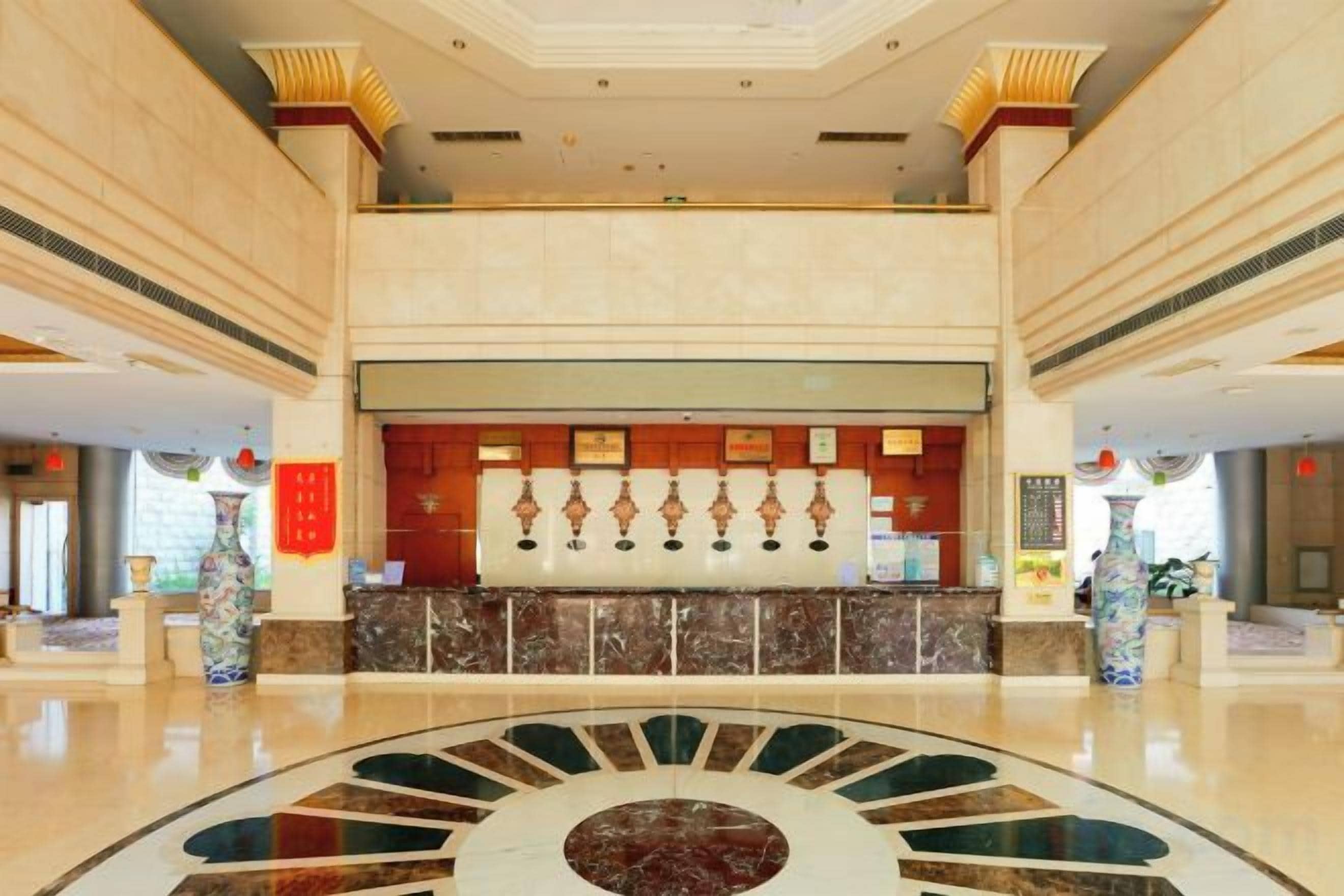 A spacious lobby with a marble reception desk, large windows, and a central decorative feature.