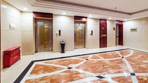 A hotel lobby with a marble floor, elevators, and a red storage unit. - Cangzhou Yihe Hotel (Cangzhou)