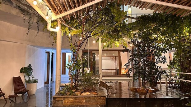 Um pátio interno com fonte, assentos e vegetação.