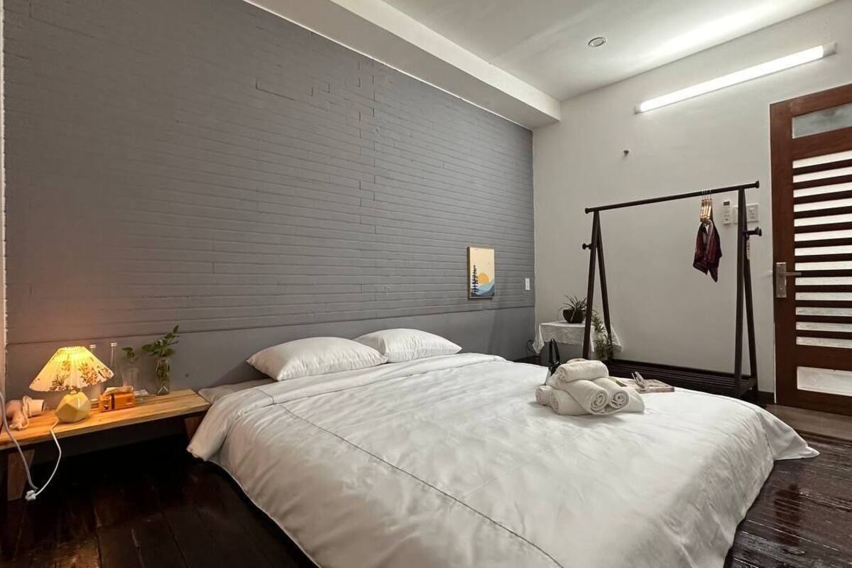 A modern bedroom with a large bed, a bedside table with a lamp, and a wooden headboard.