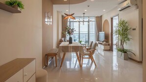 A modern dining area with a table, chairs, and a hanging light fixture. - Vinhomes Urban Apartment HCM (Ho Chi Minh City)