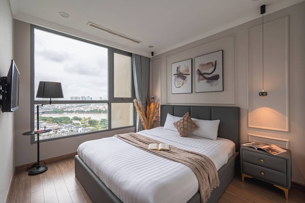 Ein modernes Schlafzimmer mit großem Fenster, einem Bett mit Blick, einem Nachttisch und einem beistelligen Tisch.