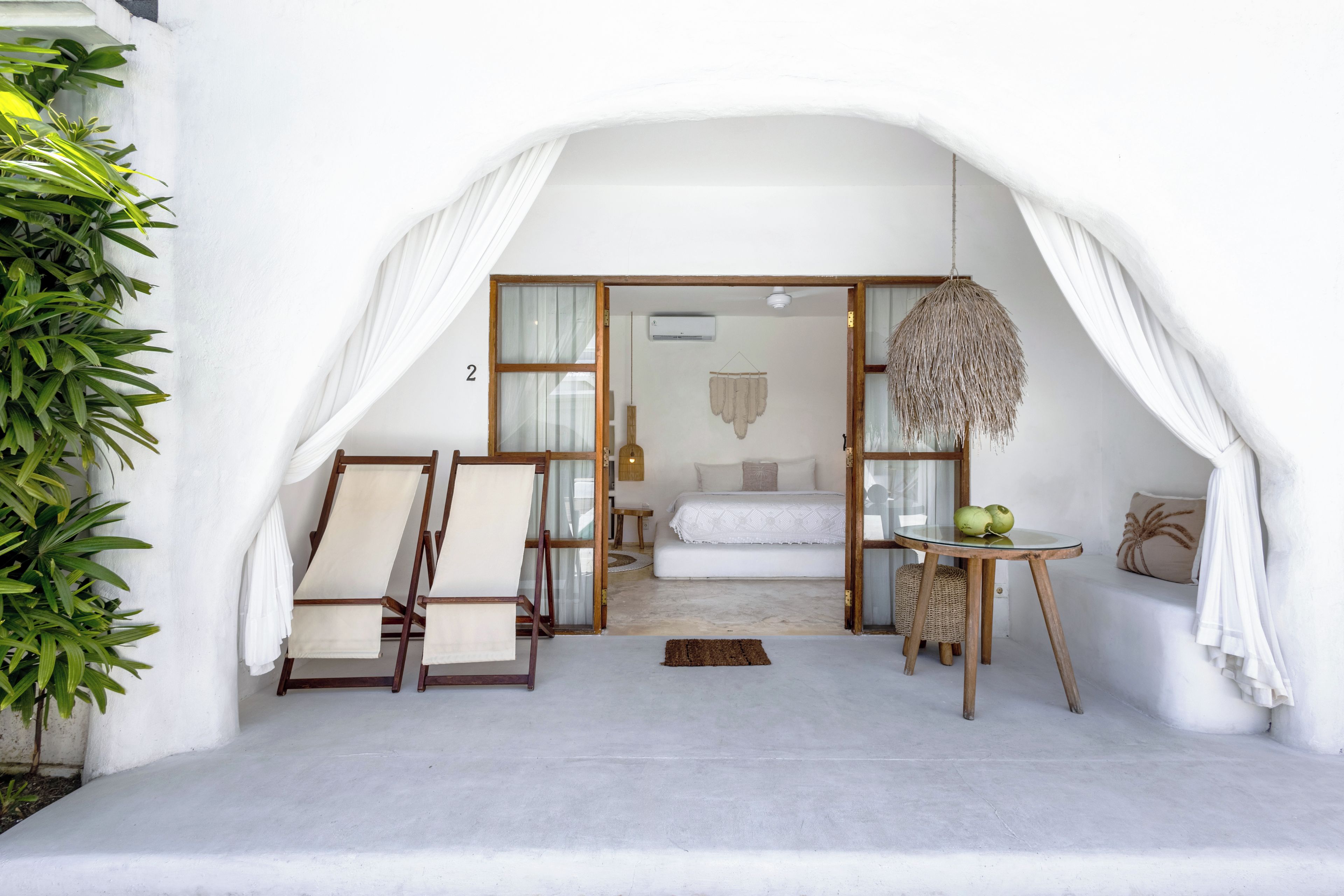 A room with a bed, a hanging light fixture, and a small table with a plant.