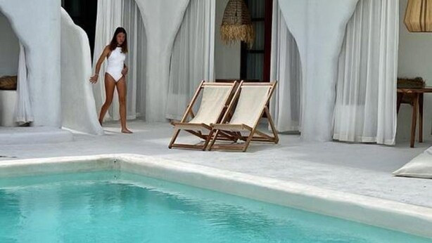 A pool area with a clear blue pool, white walls, and a person in a swimsuit. - Sal Central (Pecatu)