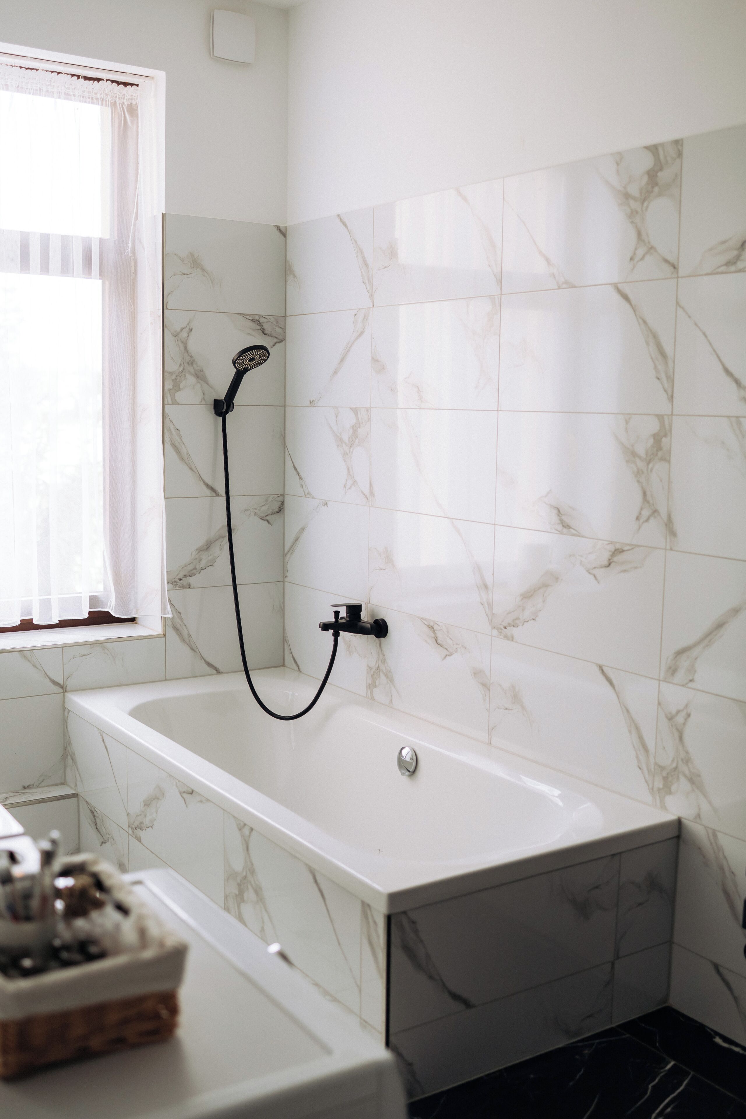 Un baño con bañera, ducha y ventana con cortinas.