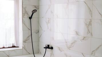 Un baño con bañera, ducha y ventana con cortinas.
