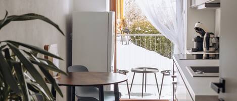 A compact kitchen with a dining area, a potted plant, and a view of the outdoors.