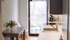 Una cucina funzionale con angolo ristoro, un orologio appeso al muro e vista attraverso la porta.