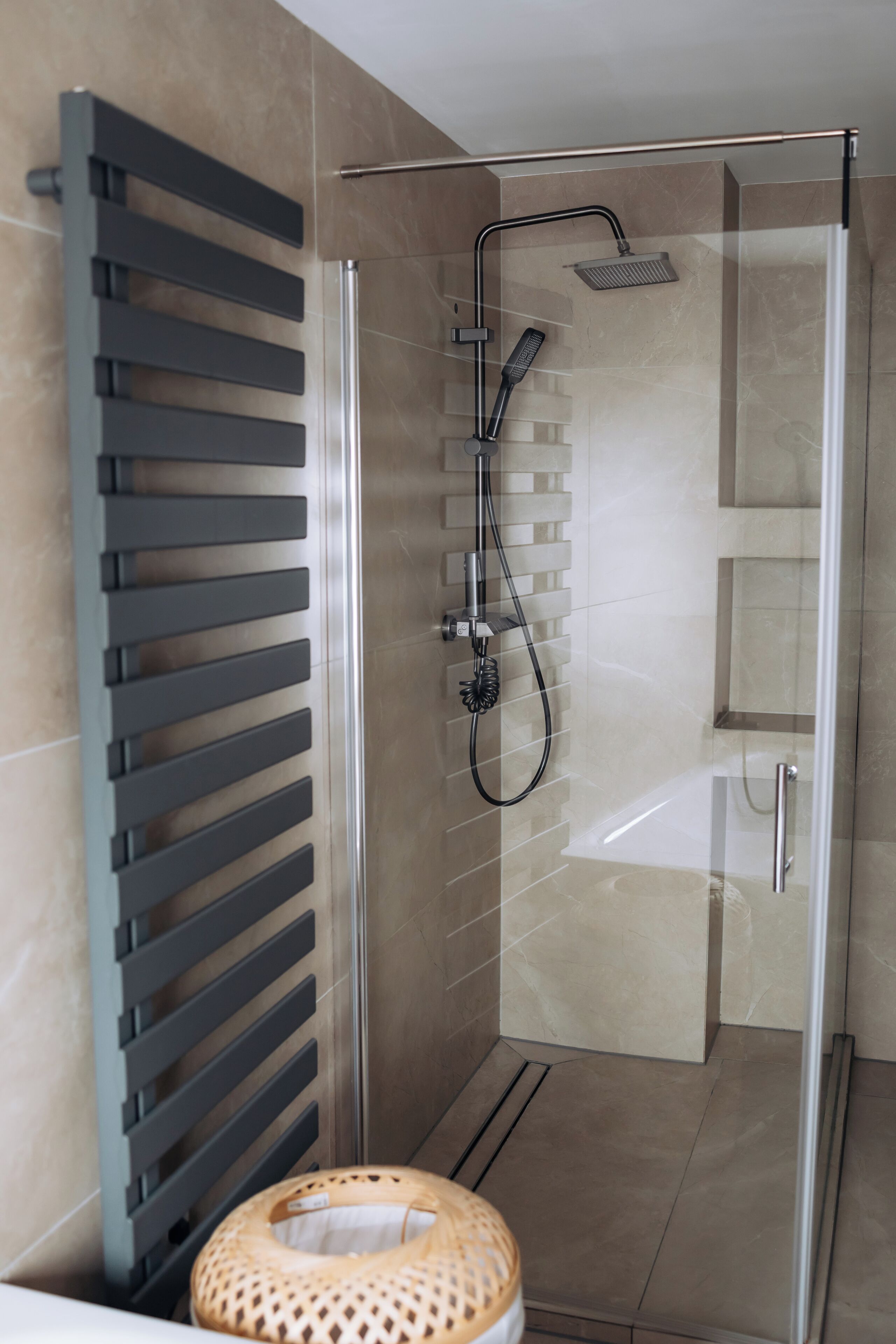 Un baño moderno con cabina de ducha de vidrio, un perchero y un taburete de madera.