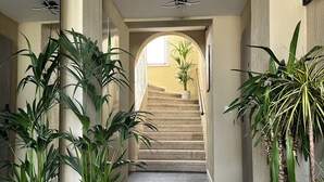 Un corridoio con piante in vaso, una scala e un ventilatore a soffitto.
