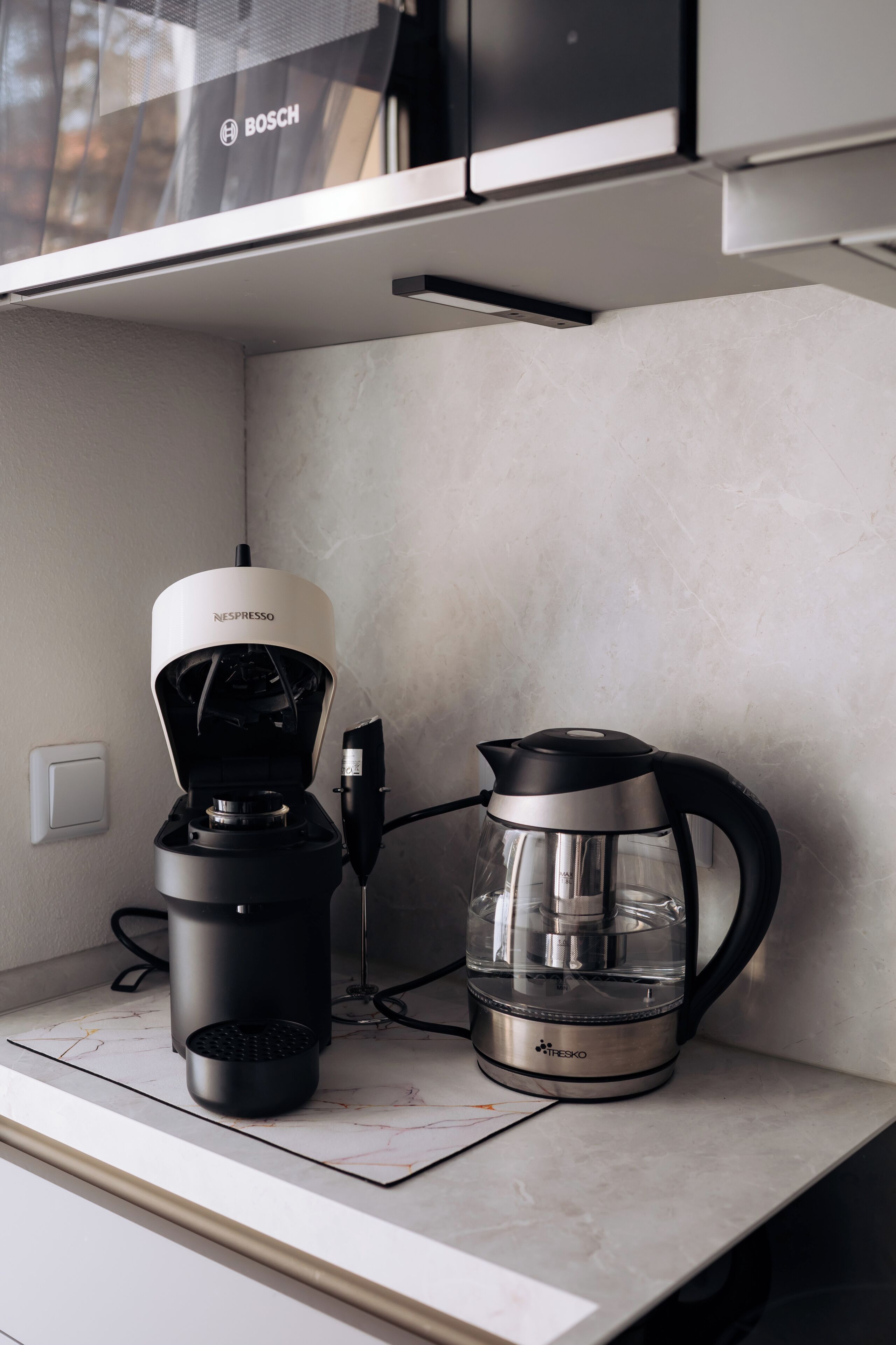 A kitchen with a coffee maker and a water kettle on the counter.