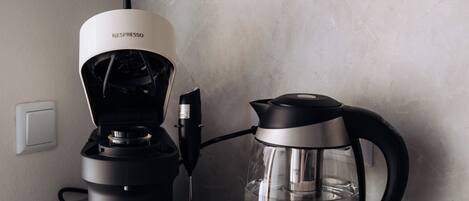 A kitchen with a coffee maker and a water kettle on the counter.