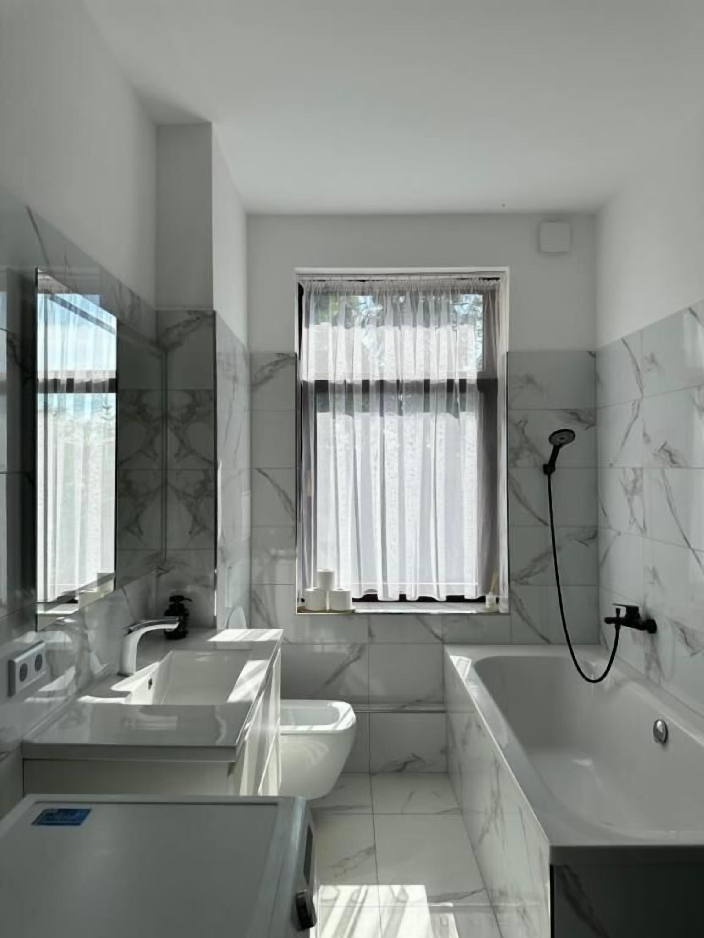 A modern bathroom with a bathtub, a shower, and a sink.
