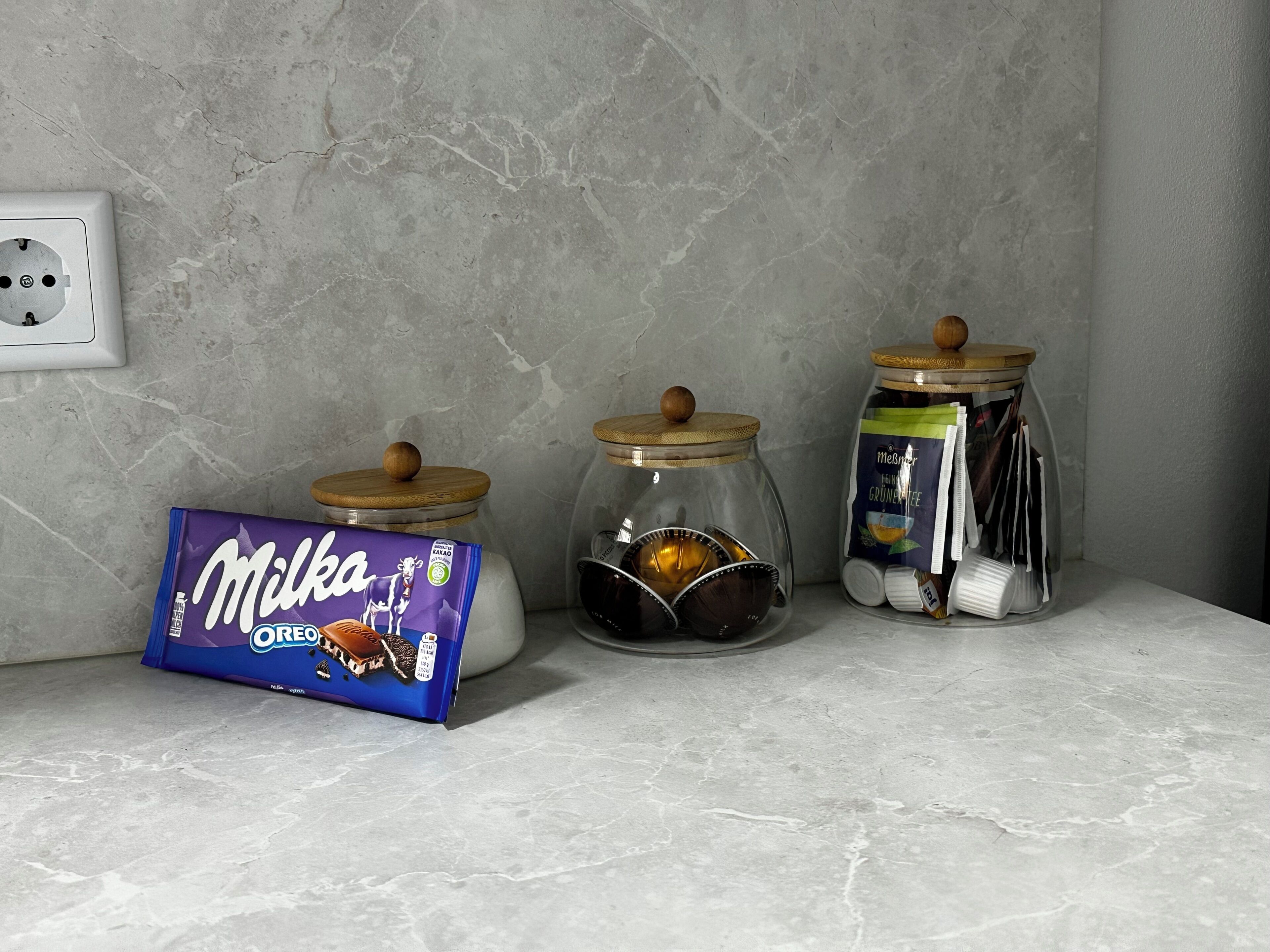Eine Küchenarbeitsplatte mit drei Gläsern, einer Packung Milka Oreo Keksen und einer Steckdose.