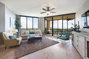 A spacious living room with a large window, a ceiling fan, and a balcony with outdoor furniture. - Largest Floor Plan with Fabulous 11th Floor River Views! (Cape Coral)