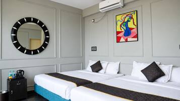 A hotel room with a large bed, a round mirror, an air conditioning unit, and a colorful abstract painting.
