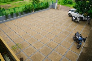 A paved outdoor area with a scooter and a car parked. - GP Golden Palm Meadows Resorts (Bhatkal)